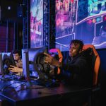 Two gamers intensely focused in a professional eSports competition with vibrant game visuals. — Play Baccarat Confidently on