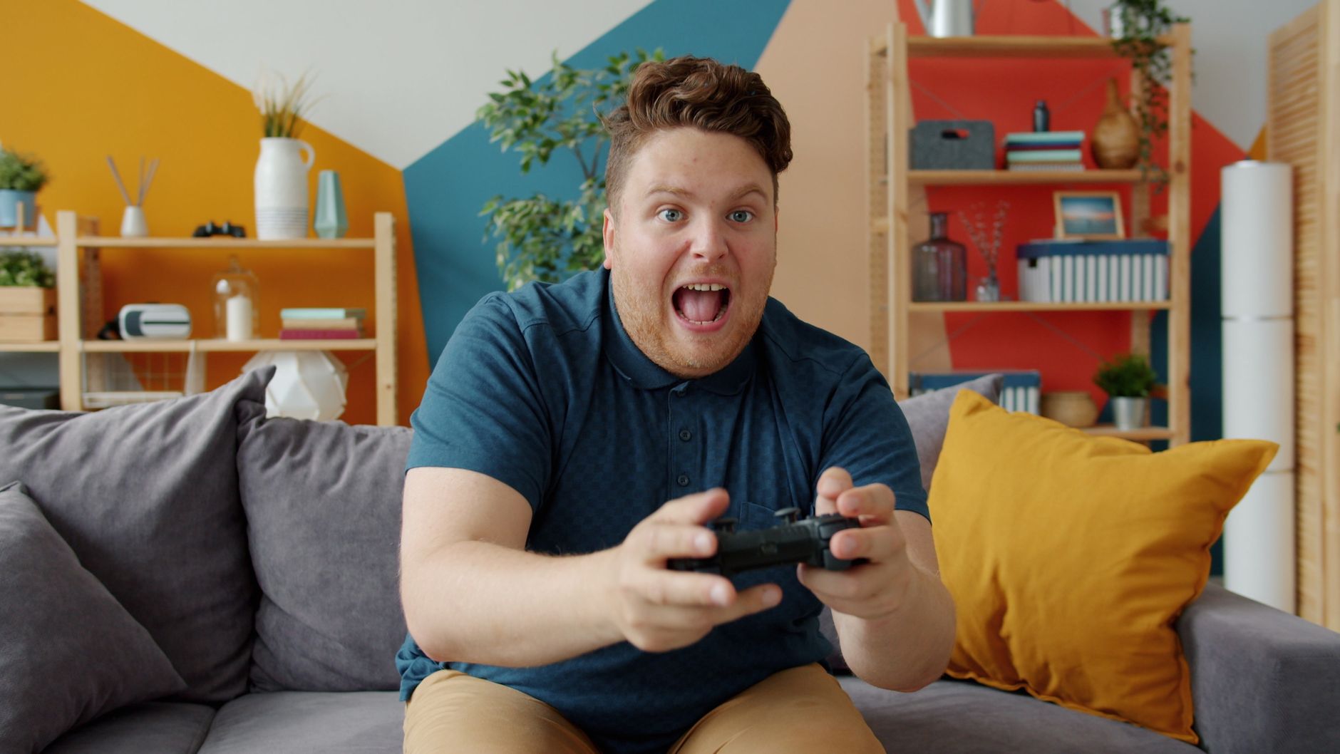 Enthusiastic adult male playing video game on console in colorful, modern living room. — Rewards and Bonuses: A Highlight of