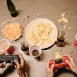 Two gamers playing video games with snacks and drinks on table, a perfect setup for gaming night. — UFA656 Online Casino Serv